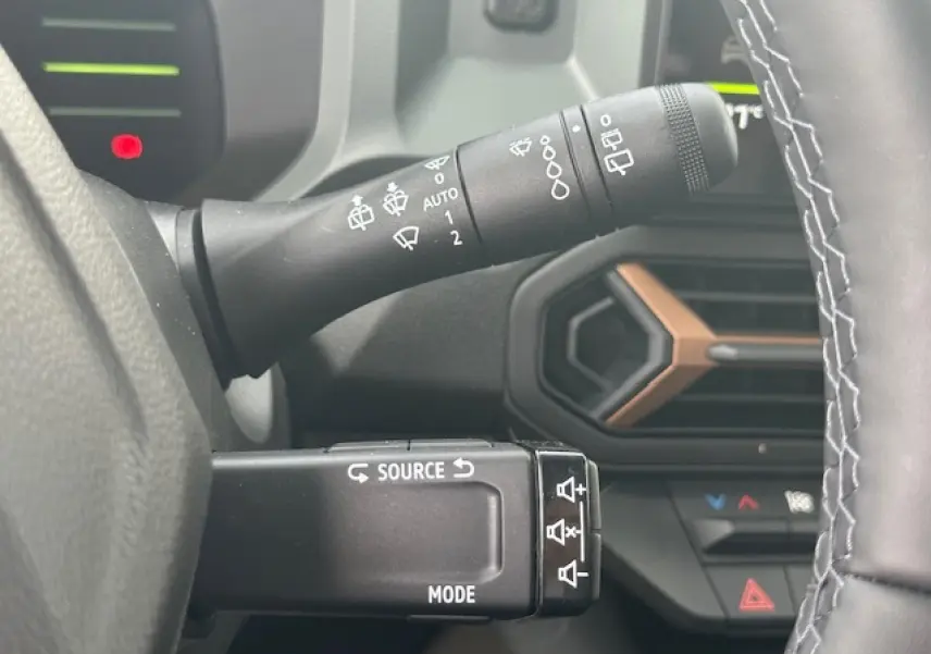 Gros plan sur les commandes au volant du Dacia Duster gris schiste, avec détails des commandes d'essuie-glace et multimédia.