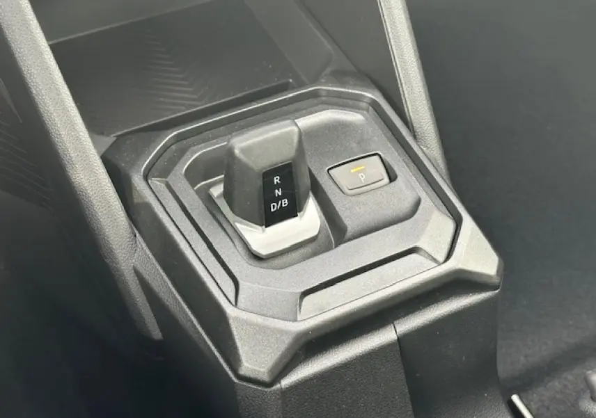 Gros plan sur le levier de vitesses automatique et bouton de parking du DACIA DUSTER III 1.6 Hybrid 2025, intérieur noir.