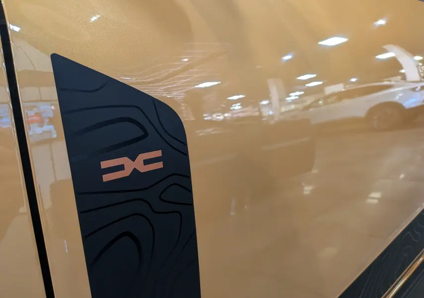 Détail du logo Stepway noir et cuivre sur la porte beige Safari d'une Dacia Sandero Stepway TCe 110 2025.