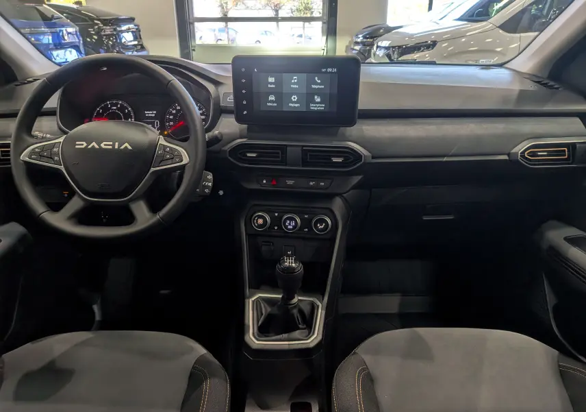 Vue intérieure frontale du tableau de bord de la Dacia Sandero Stepway TCe 110, avec écran tactile et volant multifonction.