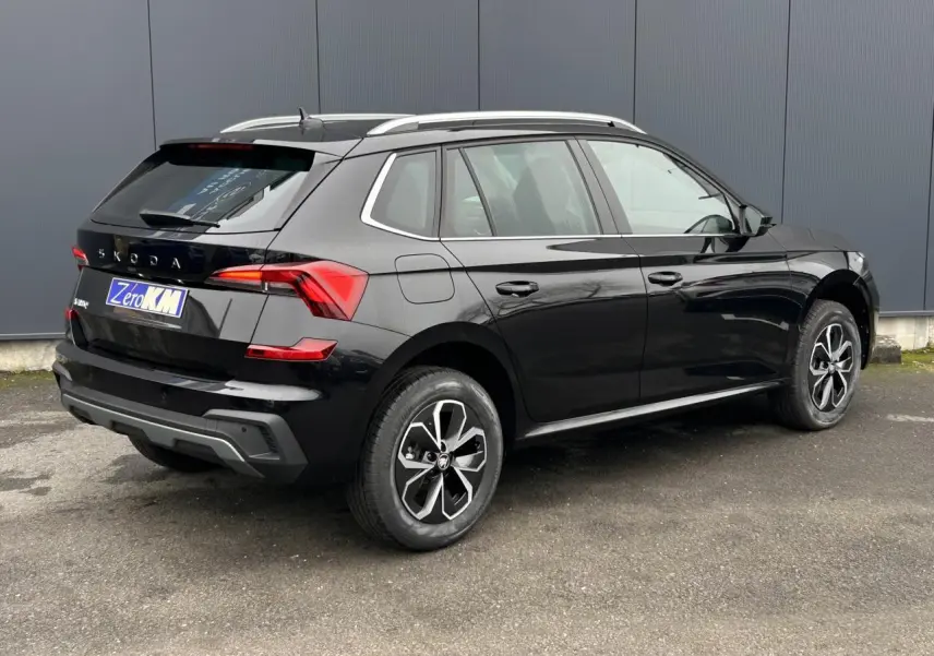 Vue 3/4 arrière droite d'un Skoda Kamiq noir Magic avec jantes alliage et baguettes chromées visibles.