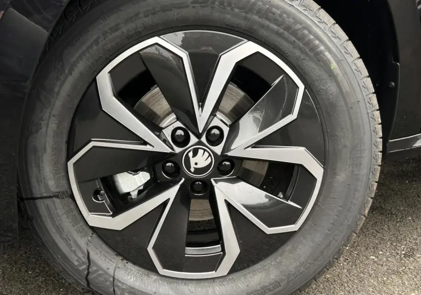Gros plan sur la jante alliage noire et argentée du Skoda Kamiq noir Magic, mettant en valeur le logo central.
