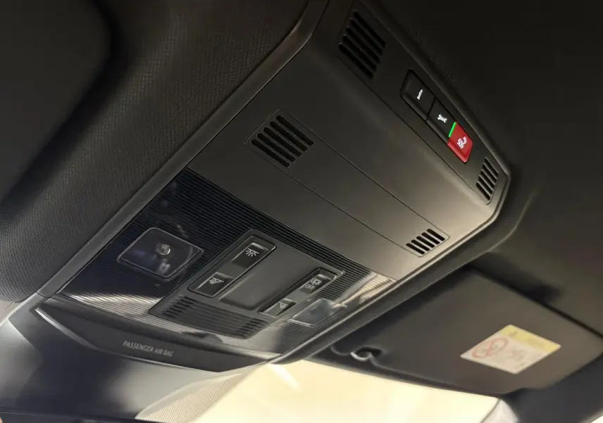 Vue en contre-plongée du plafonnier noir du Volkswagen T-Roc 2025 avec commandes d'éclairage et bouton SOS rouge.