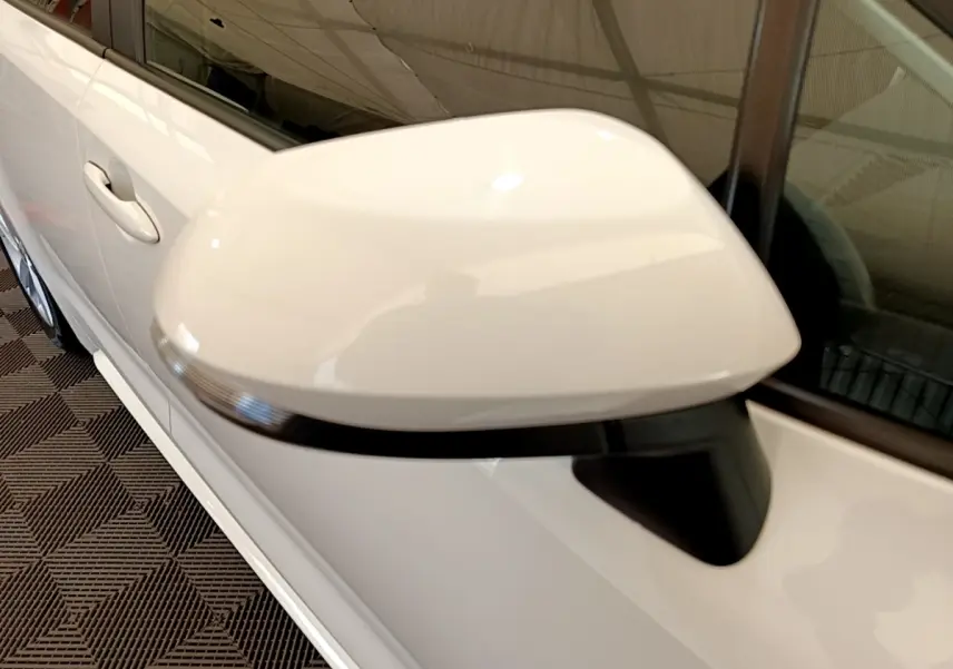 Gros plan sur le rétroviseur droit blanc de la Toyota Corolla hybride 2022, avec la portière et la poignée visibles.
