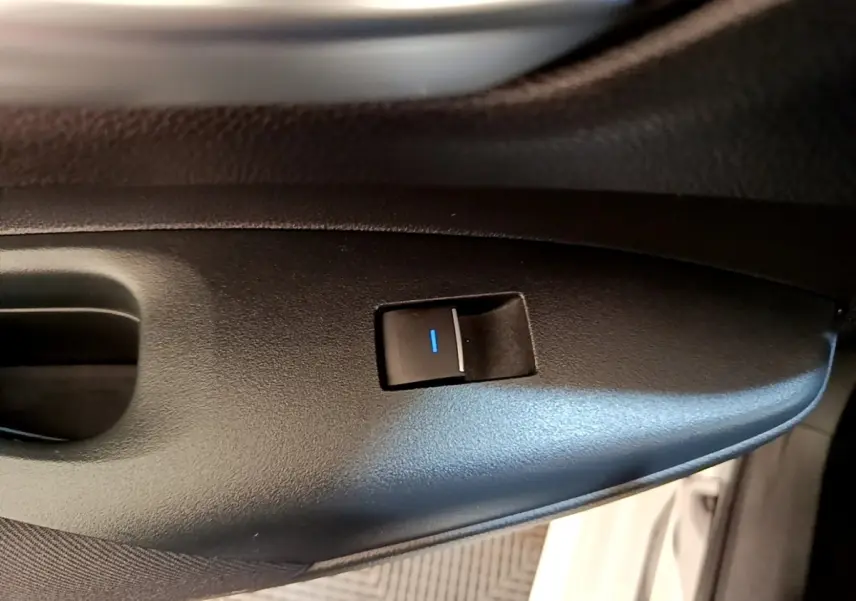 Gros plan sur l'interrupteur de verrouillage des portes côté conducteur d'une Toyota Corolla blanche hybride 2022.