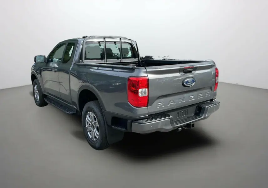Ford Ranger gris carbone en 3/4 arrière droit, mettant en valeur la benne ouverte et l'attelage robuste.