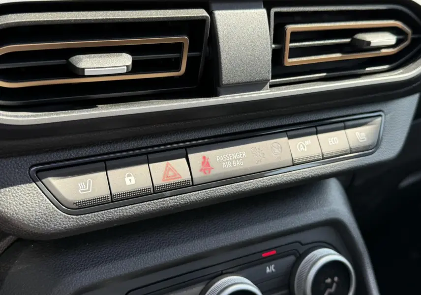 Gros plan sur la console centrale du Dacia Sandero Stepway 2025, boutons de confort et ventilation noire.