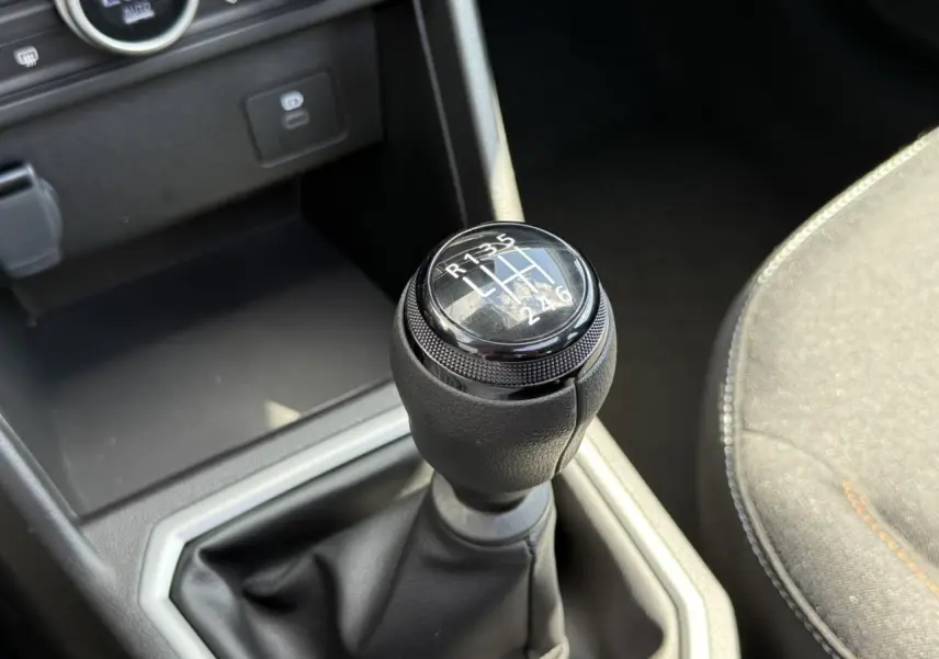 Gros plan sur le levier de vitesses manuel noir de la Dacia Sandero Stepway 2025, intérieur gris et noir.