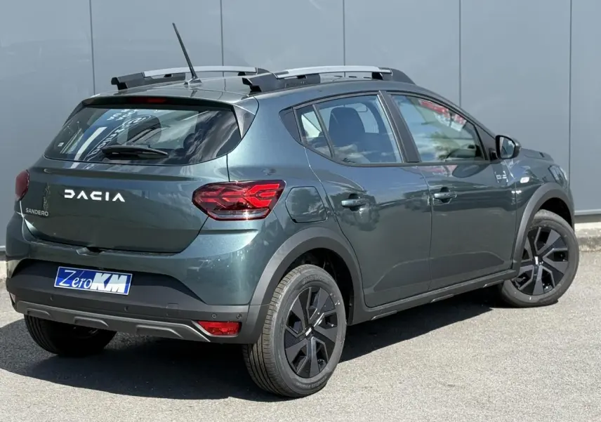 Vue 3/4 arrière droite d'une Dacia Sandero Stepway Vert Cèdre avec barres de toit et jantes 16 pouces noires.