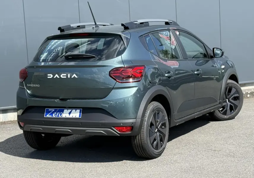 Vue 3/4 arrière droite d'une Dacia Sandero Stepway Vert Cèdre avec barres de toit et jantes 16 pouces noires.