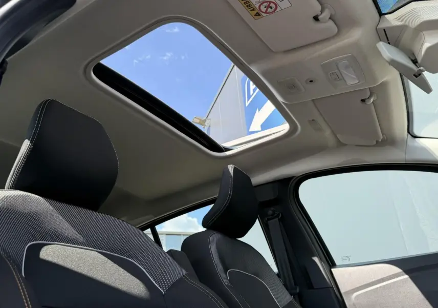 Vue intérieure avant de la Dacia Sandero Stepway 2025 avec toit ouvrant électrique et sièges noirs à surpiqûres blanches