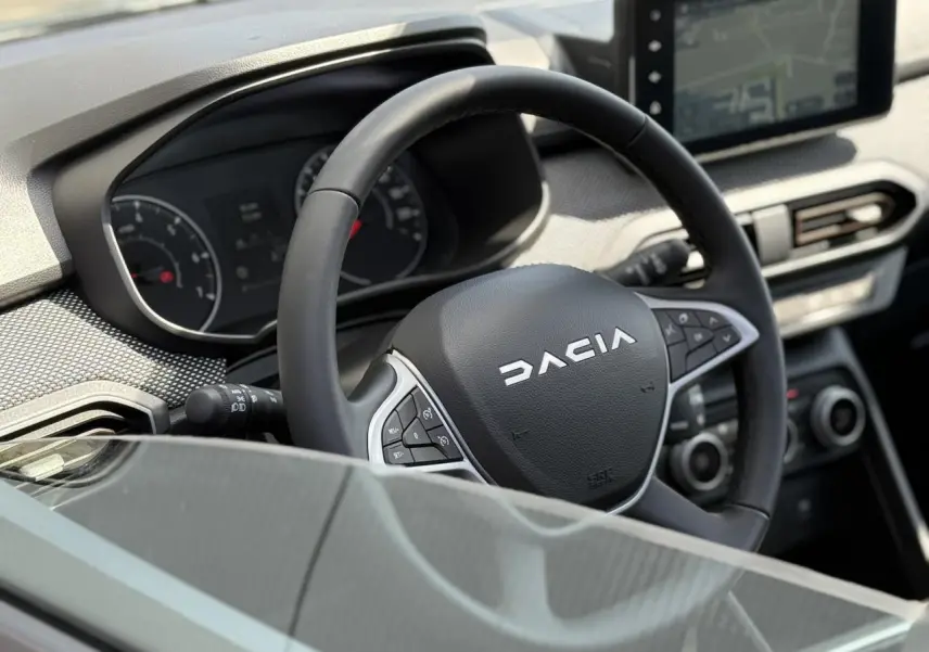 Vue rapprochée du volant Dacia et du tableau de bord numérique du Sandero Stepway 2025, ambiance intérieure moderne.