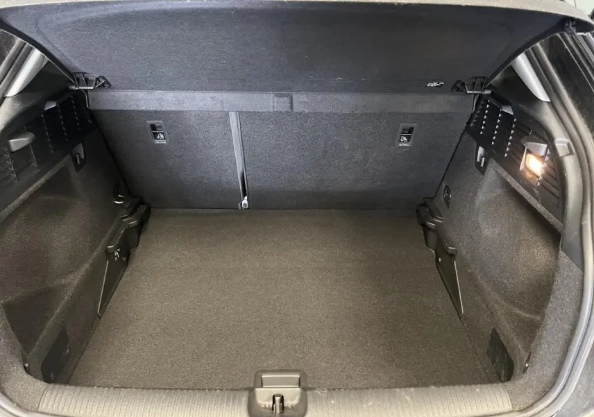 Coffre ouvert de l'Audi Q2 2023 noir, vue arrière montrant l'espace de chargement et l'éclairage intérieur à droite.