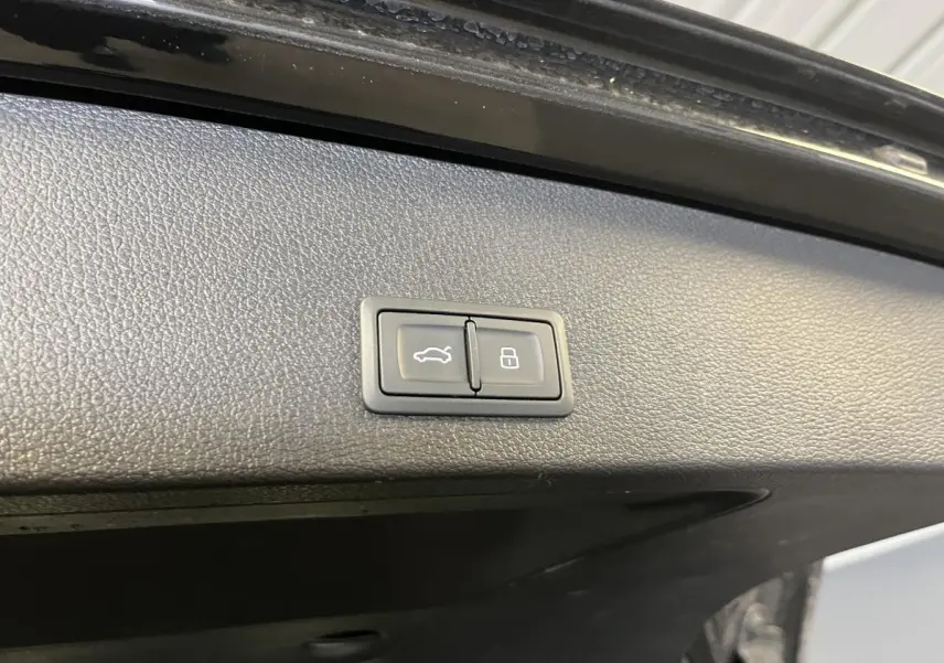 Boutons d'ouverture et de verrouillage du coffre sur la garniture intérieure du hayon noir d'un Audi Q2 2023.