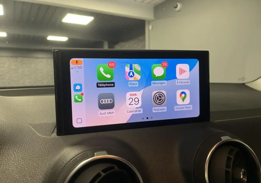 Écran tactile central affichant l'interface Apple CarPlay dans l'habitacle d'un Audi Q2 noir 2023.