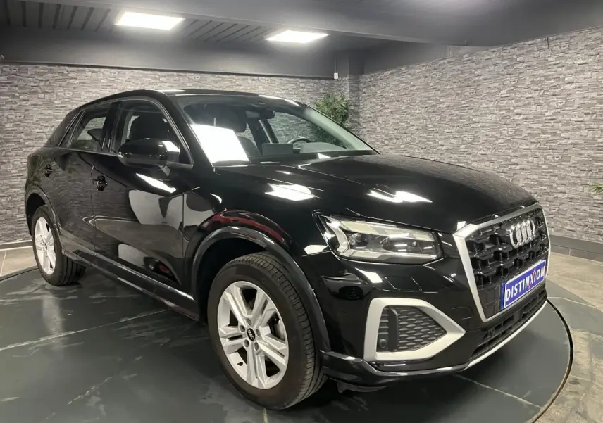 Audi Q2 2023 noir brillant vue 3/4 avant droit avec calandre hexagonale et jantes 5 branches doubles.