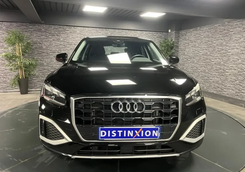 Audi Q2 noir brillant vue de face dans un showroom avec calandre hexagonale et éclairage LED distinctif.