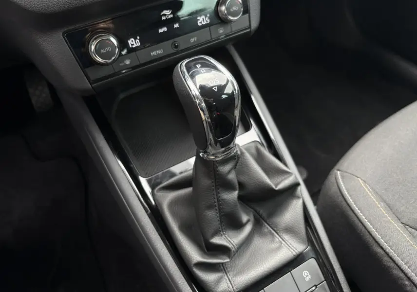 Le levier de vitesse automatique noir et chrome du Skoda Kamiq TSI 110 DSG Ambition vu de dessus avec console et siège gris.