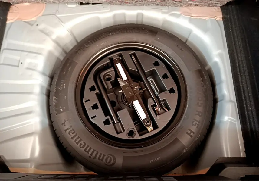 Gros plan sur la roue de secours et les outils de bord dans le coffre d'une Renault Clio Business TCe 100 gris clair.