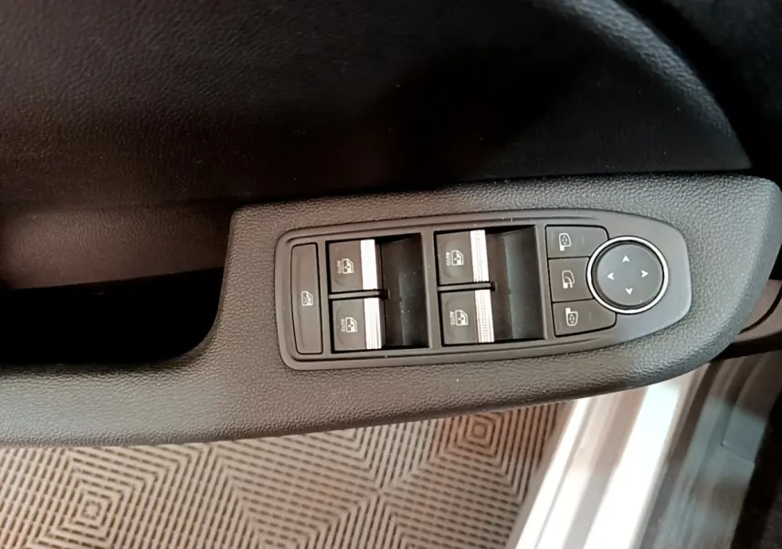 Gros plan sur la commande des vitres et rétroviseurs côté conducteur d'une Renault Clio Business gris clair de 2020.