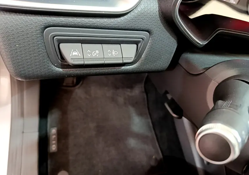 Gros plan sur les commandes d'assistance au conducteur à gauche du volant d'une Renault Clio Business TCe 100 gris clair de 2020.