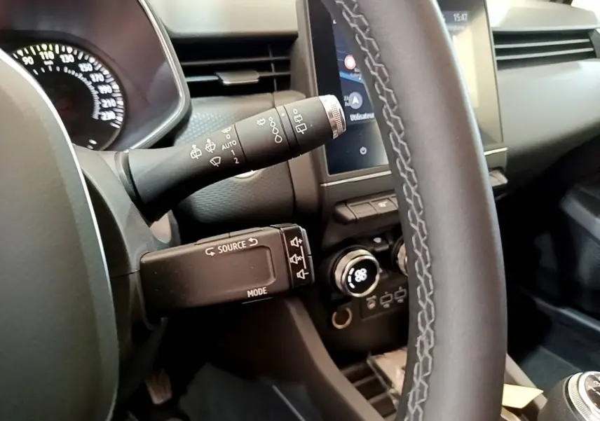 Vue rapprochée du volant et commandes du tableau de bord d'une Renault Clio Business TCe 100 gris clair, avec écran tactile.