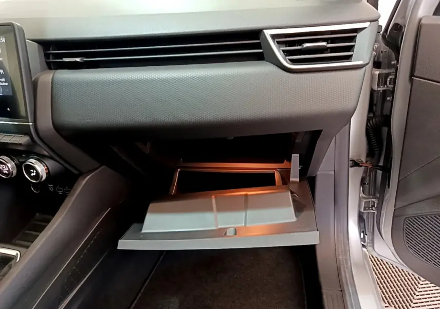 Vue intérieure côté passager de la Renault Clio Business TCe 100 2020 gris clair, boîte à gants ouverte et tableau de bord moderne.