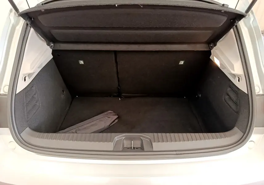 Coffre ouvert vu de l'arrière d'une Renault Clio Business TCe 100 gris clair, intérieur noir et espace de rangement vide.