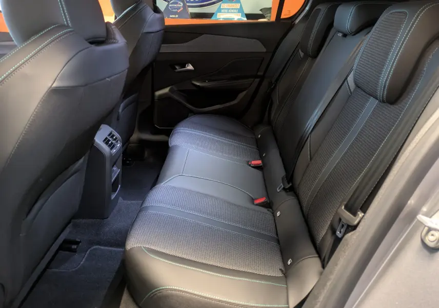 Vue intérieure côté droit sur la banquette arrière en cuir noir avec surpiqûres bleues de la Peugeot 308 2025 gris Artense.