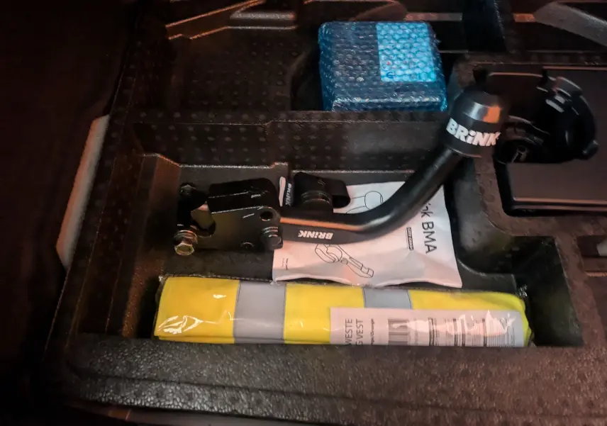 Gros plan sur le coffre de la Peugeot 308 2025 gris Artense montrant un kit d'attelage Brink et un gilet jaune.