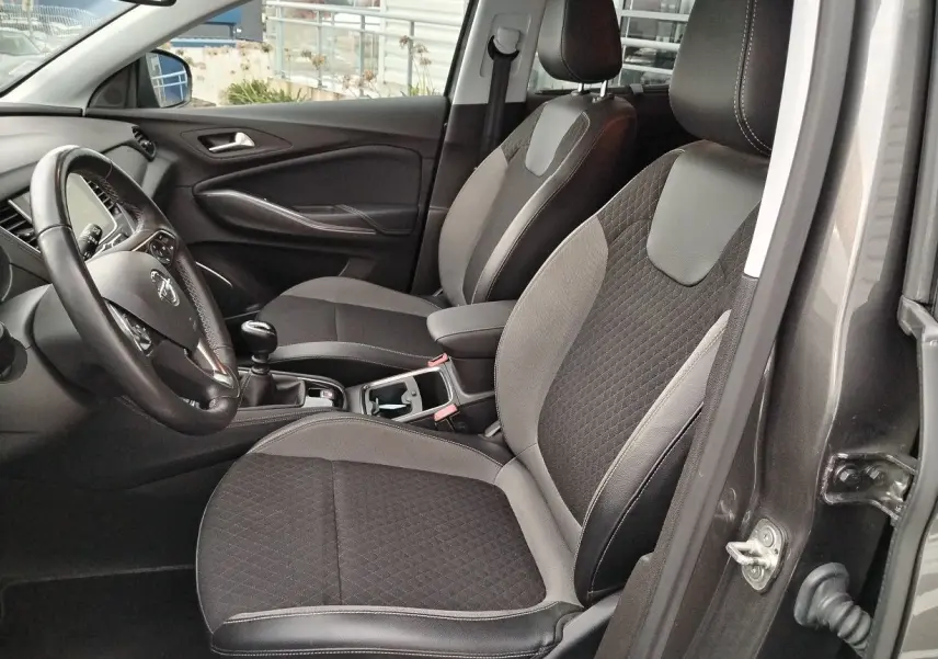 Vue intérieure côté conducteur de l'Opel Grandland X gris platinium, sièges tissu et cuir noir avec coutures contrastées.