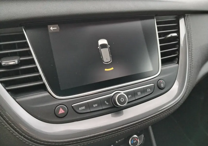 Écran tactile central de l'Opel Grandland X 2019 affichant l'aide au stationnement, entouré de commandes audio et navigation.