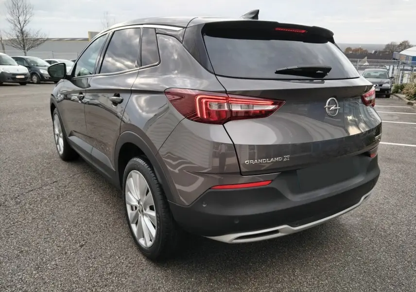 Vue 3/4 arrière droite d'un Opel Grandland X gris platinium avec feux arrière LED et jantes alliage.