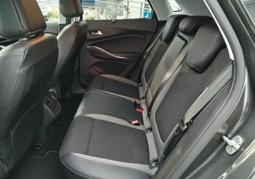 Vue intérieure arrière côté droit de l'Opel Grandland X gris platinium, mettant en valeur les sièges en tissu et cuir noir avec surpiqûres grises.