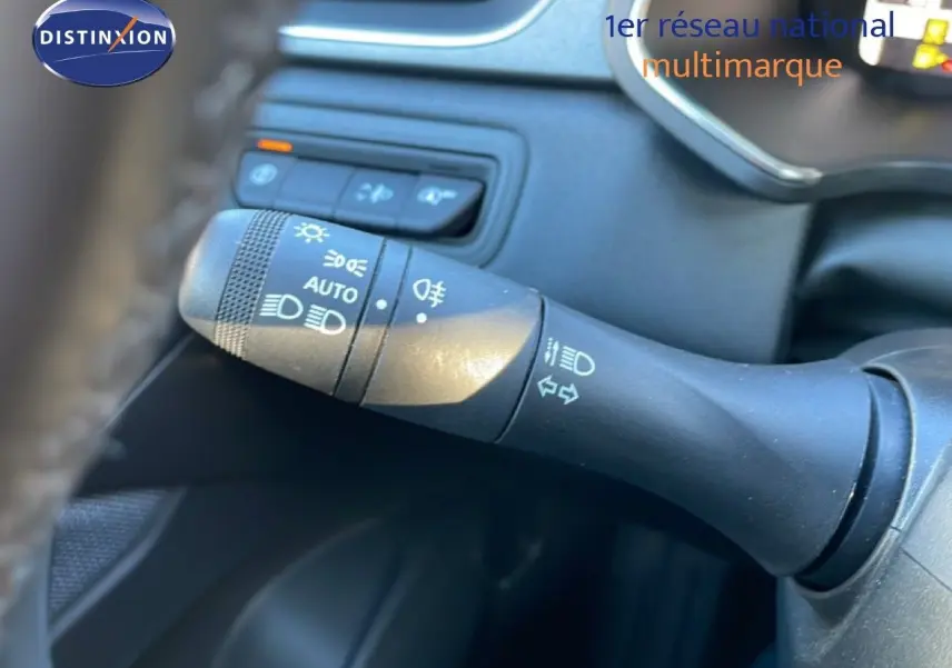 Gros plan sur la commande de phares et clignotants à gauche du volant d’un Renault Captur rouge désir métal avec toit noir.