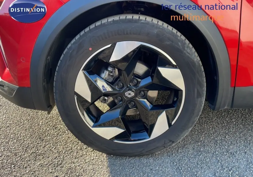 Gros plan sur la roue avant droite du Renault Captur rouge Désir Métal avec jante noire et argentée au design géométrique.