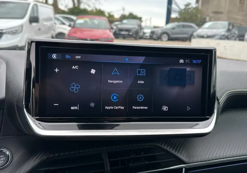 Vue intérieure centrée sur l'écran tactile du tableau de bord de la Peugeot 208 gris 2025, affichant les options de navigation et connectivité.