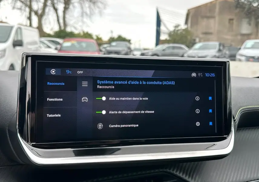 Écran tactile du tableau de bord de la Peugeot 208 Hybrid 110 gris, affichant les aides à la conduite avancées.