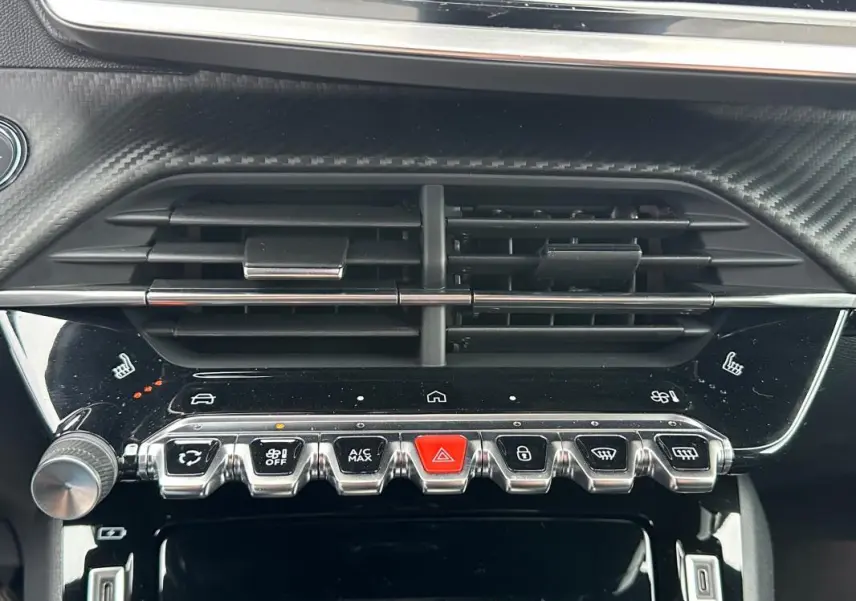 Vue rapprochée du tableau de bord gris de la Peugeot 208 Hybrid 110 e-DCS6 GT, avec commandes climatisation et ventilation.