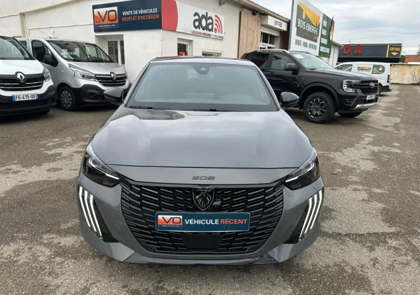 Vue frontale d'une Peugeot 208 Hybrid 110 e-DCS6 GT gris 2025 avec feux LED verticaux et calandre noire distinctive.