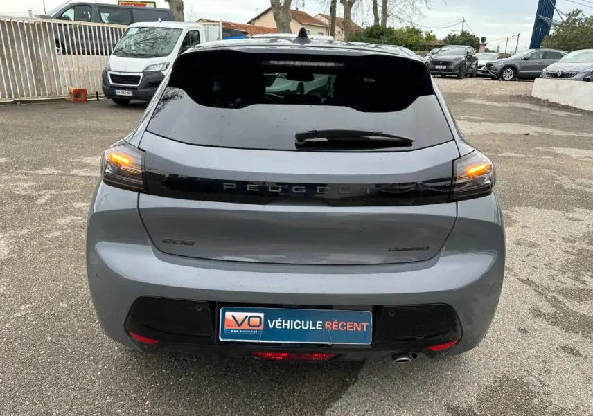 Vue arrière d’une Peugeot 208 Hybrid 110 gris, feux arrière allumés et jantes alliage visibles.