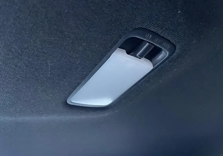 Plafonnier intérieur blanc sur ciel de toit noir du Nissan Juke II bleu magnetic 2024.