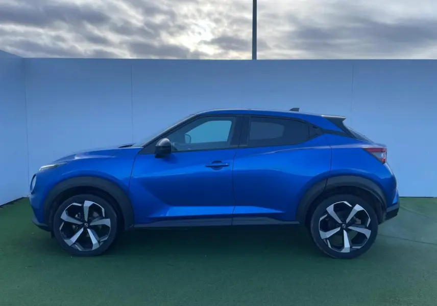 Profil côté gauche du Nissan Juke 2 bleu magnetic 2024 avec jantes alliage noires et vitres teintées.