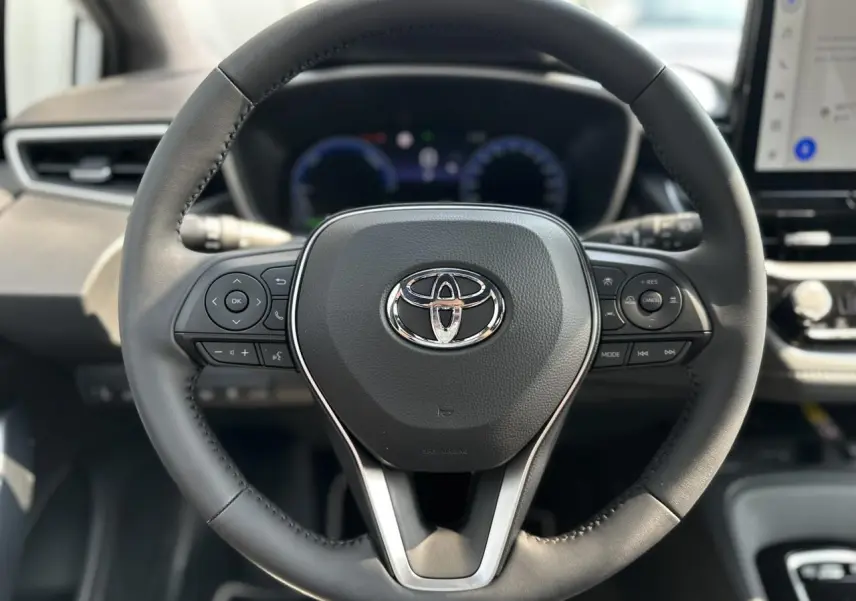 Vue rapprochée du volant multifonction noir avec logo Toyota au centre dans le cockpit de la Corolla Touring Sport 2025.