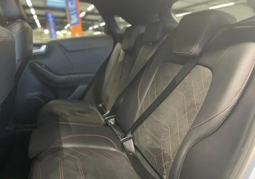 Vue intérieure côté gauche des sièges arrière en suédine et vinyle noir avec surpiqûres rouges du Ford Puma 2024 gris clair.