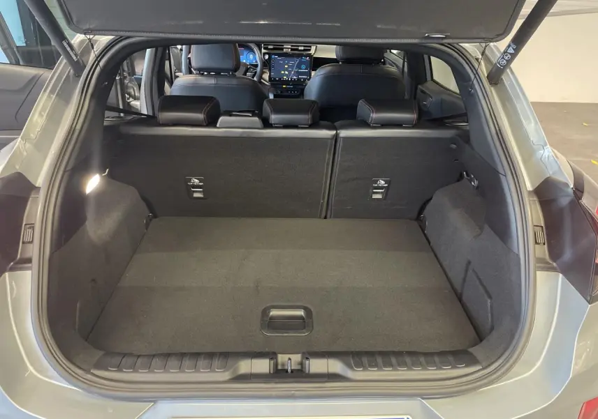 Coffre ouvert vue arrière du Ford Puma gris clair 2024, avec banquette arrière et tableau de bord visible.