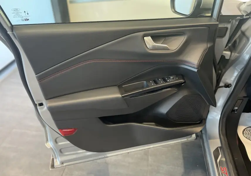 Vue rapprochée de la porte avant gauche du Ford Puma gris clair, avec garniture noire et surpiqûres rouges.