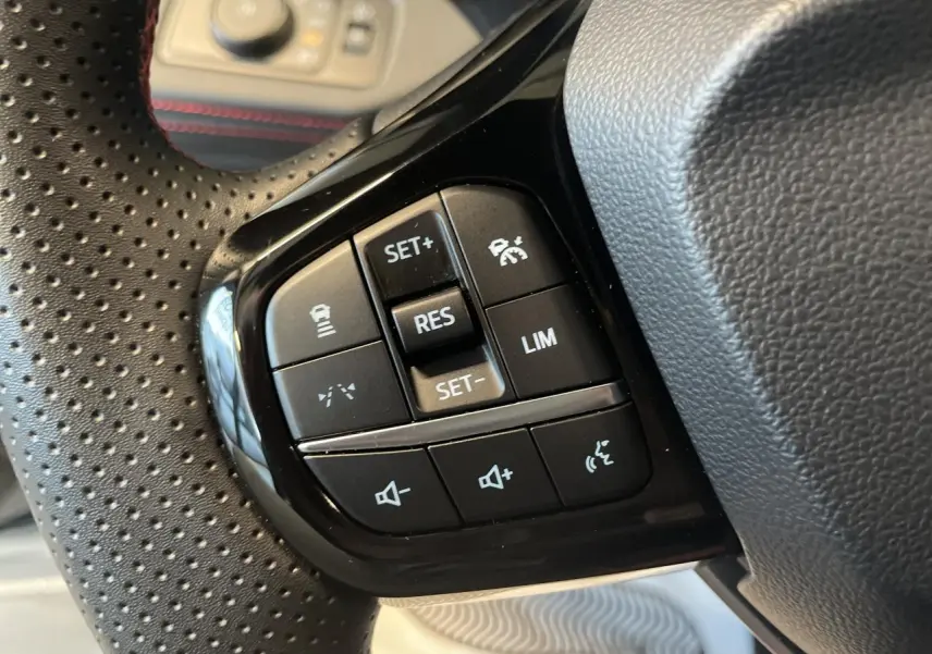 Gros plan sur les commandes du volant perforé noir du Ford Puma 2024, avec boutons de régulateur et volume sonore.