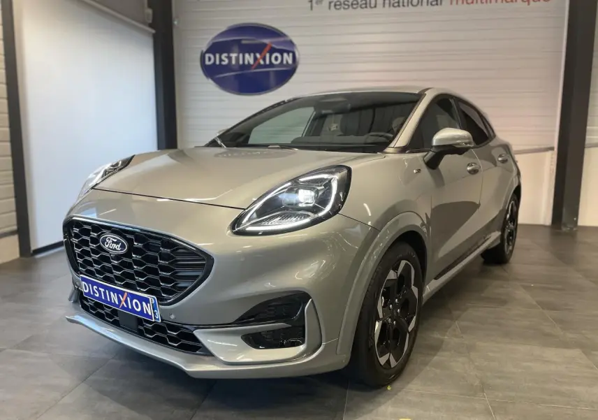 Ford Puma gris clair en 3/4 avant droit, avec calandre noire et jantes alliage noires distinctives.