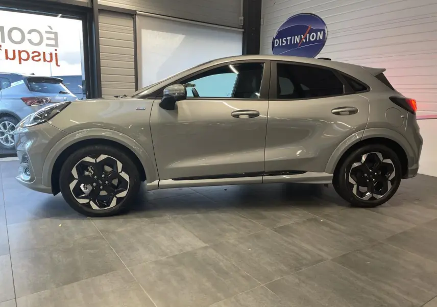 Ford Puma gris clair en vue de profil côté gauche, avec jantes alliage noires et détails ST Line visibles.